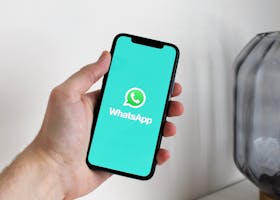 Close-up of a hand holding a smartphone displaying the WhatsApp app screen.
